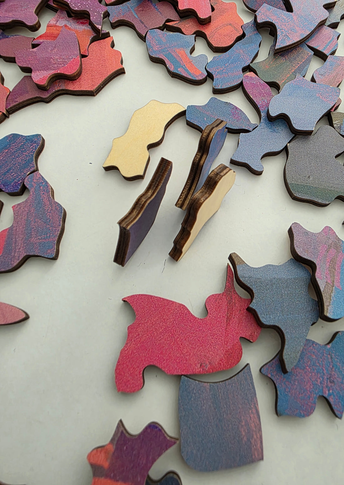 Pieces on edge: Lumenea puzzle pieces standing on edge, showing 4mm basswood layers and bare wood backs.